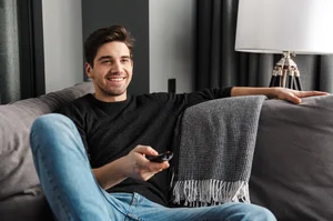 Person relaxing on a sofa while watching television in a modern living room.